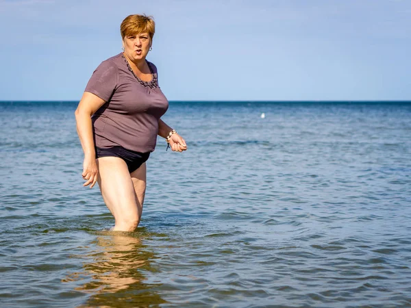 Mogen kvinna som går på vattnet i havet. — Stockfoto