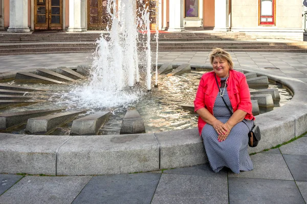 Donna matura in rosso che cammina per il centro storico. Tallinn — Foto Stock