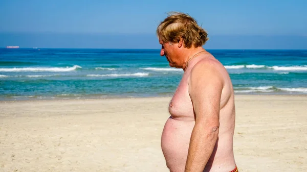 Un uomo anziano con le pinne appoggiato sulla spiaggia — Foto Stock