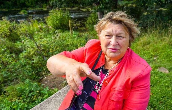 Volwassen vrouw in een rode jas rusten in het Park — Stockfoto