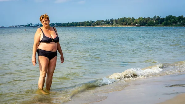 Mogen fyllig kvinna sola på stranden av havet — Stockfoto