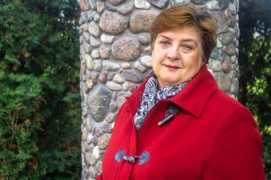 Kırmızılı olgun bir kadın eski kasabada yürüyor.