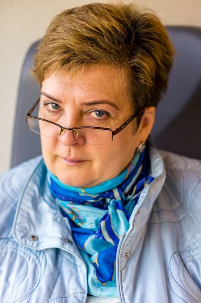 Pensive Femme mûre dans des lunettes et une écharpe bleue promenades en train — Photo