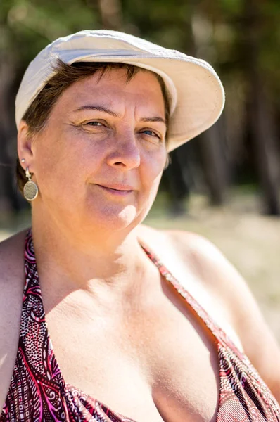 Dojrzała, pulchna kobieta i biała czapka spoczywająca nad morzem — Zdjęcie stockowe