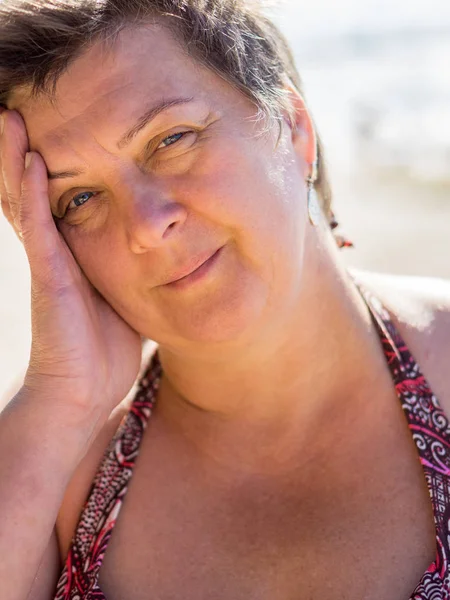 Mature, plump woman in a swimsuit resting by the sea