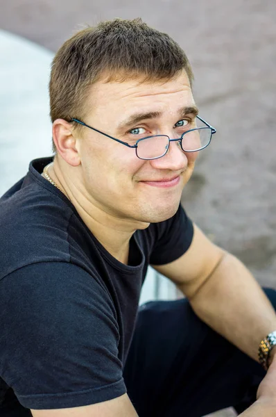 Cheerful guy in glasses smiles and looks at the camera. — Stock Photo, Image