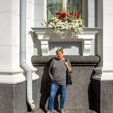 Olgun, tombul bir kadın eski şehrin sokaklarında yürüyor. Kameraya gülümsüyor. Güneş ışığı