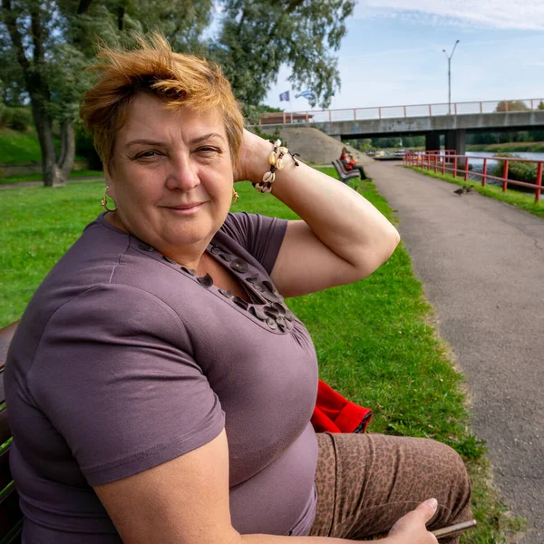 Munter Moden Kvinde Smilede Til Fotografen Sidder Bænk Ved Floden - Stock-foto