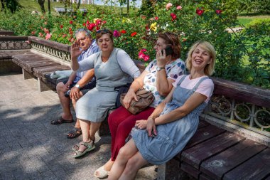 Bir grup olgun turist göl kenarındaki parkta dinleniyor.