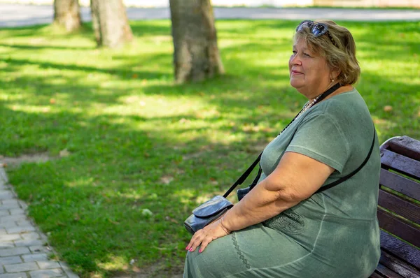 Mature plump woman with glasses resting in a city Park