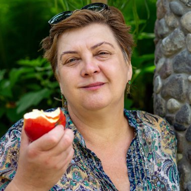 Olgun tombul kadın eski şehrin sokaklarında yürüyor. Elma yemek.