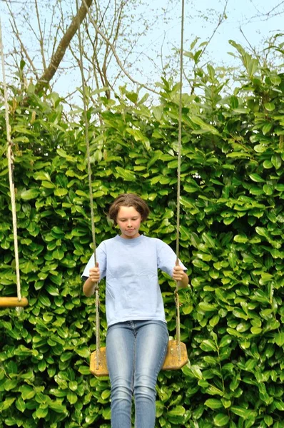 Uma menina brincando em um balanço — Fotografia de Stock