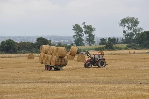 Plerin, France-August 07 2018：Tractor Harvester roll straw at — 图库照片