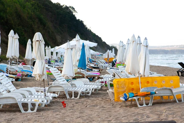 Evening sea beach with empty sunbeds and umbrellas on the sand.