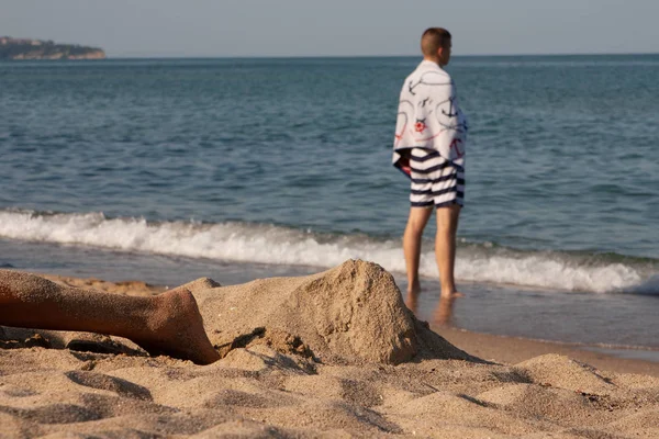 Niño con una toalla en la playa mira al mar — Foto de Stock