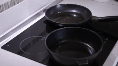 Onlar krep için hamur dökmek bir indüksiyon soba üzerinde iki kızartma tava