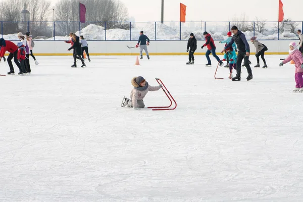 A girl rolling on the ice fell and rises. — Stock Photo, Image