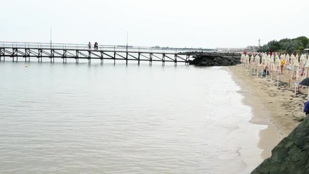 Lonely evening beach, vacationers strolling along the pier — Stock Video