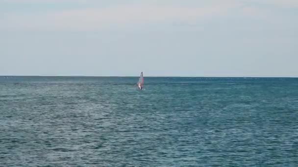 Un windsurfista nada en el mar a lo lejos . — Vídeos de Stock