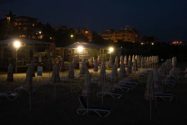 Praia noturna vazia com espreguiçadeiras e guarda-sóis vazios — Fotografia de Stock