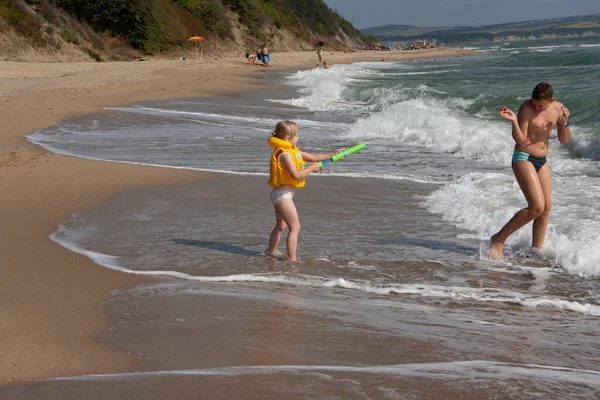 Dos niños un niño y una niña, un hermano y una hermana están jugando en la orilla del mar en el agua . — Foto de Stock