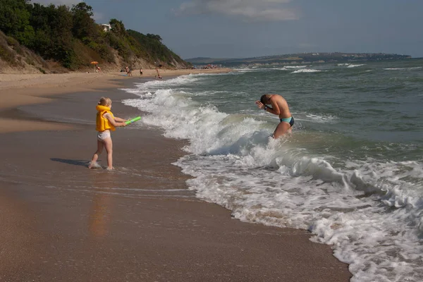 Dos niños un niño y una niña, un hermano y una hermana están jugando en la orilla del mar en el agua . — Foto de Stock