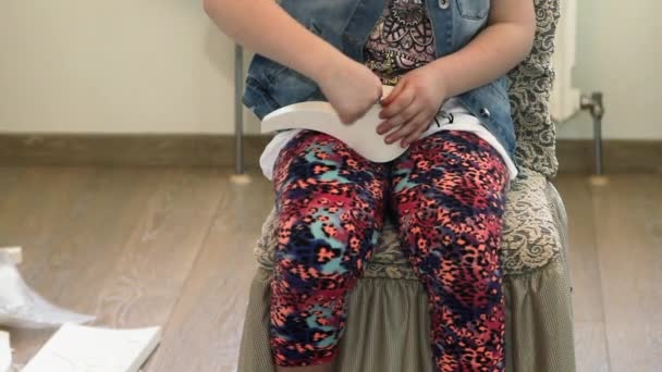 Ένα κορίτσι που κάθεται βιδώνει ένα ξύλινο πόδι από έπιπλα — Αρχείο Βίντεο