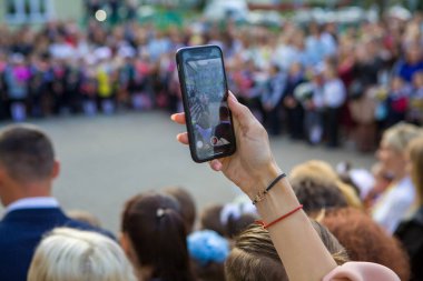 Birinci sınıf öğrencileri ve ailelerine adanmış resmi hat sırasında telefonla çekim yapmak. Minsk, Belarus, 1 Eylül 2020.