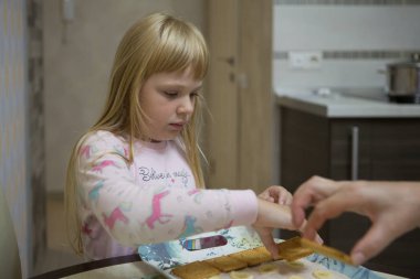 Pembe pijamalı küçük bir kız kurabiyelerden kek yapıyor..