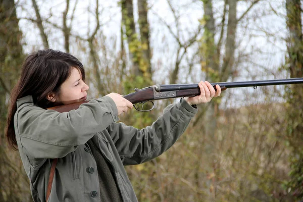 Close up of a young woman hunter aiming his gun in the field.