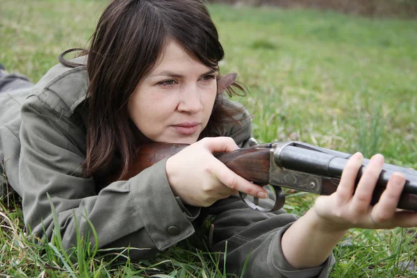 Close up of a young woman hunter aiming his gun in the field.