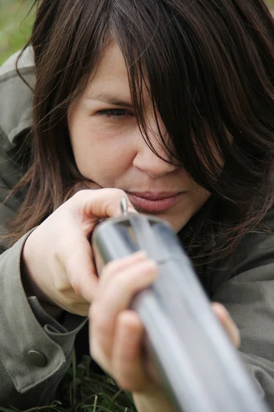 Close up of a young woman hunter aiming his gun in the field.