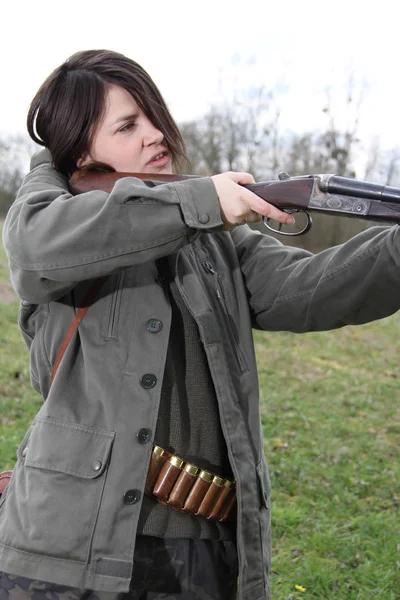 Close up of a young woman hunter aiming his gun in the field.