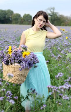 Genç caucassian esmer kadın alanındaki mor çiçekler