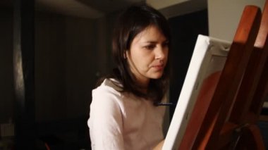 Genç kadın sanatçı kırmızı bir kalp onu art Studio şövale üzerinde beyaz bir tuval üzerine akrilik boya ile resim