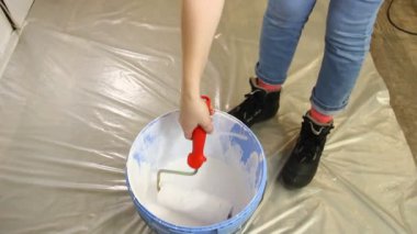 Genç kadın bir rulo ve beyaz boya ile duvar boyama