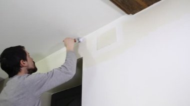 Genç adam beyaz boya ile duvar boyama