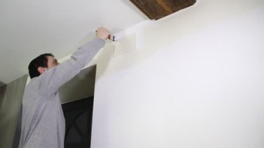 Genç adam beyaz boya ile duvar boyama