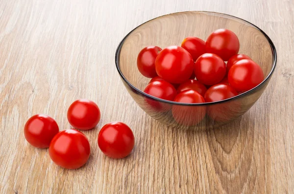 Tomato cherries in brown bowl and on wooden table