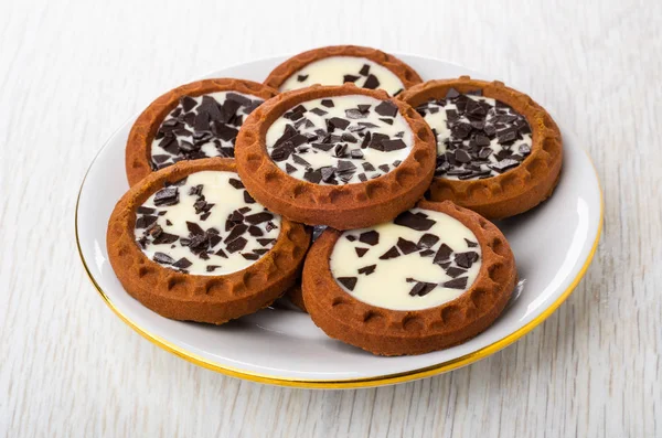 Round cookies with cream and chocolate in white plate on wooden table