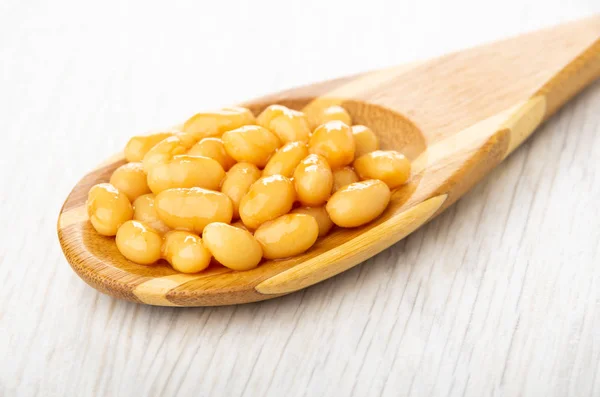 Canned bean in bamboo spoon on light wooden table