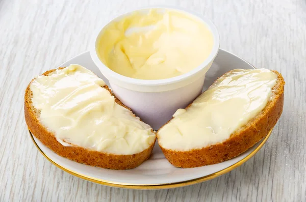 Two sandwiches with sweet melted cheese, jar of dessert cheese on white saucer on wooden table