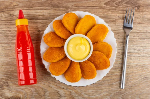 Bottle of ketchup, fried nuggets, bowl with mayonnaise in plate,