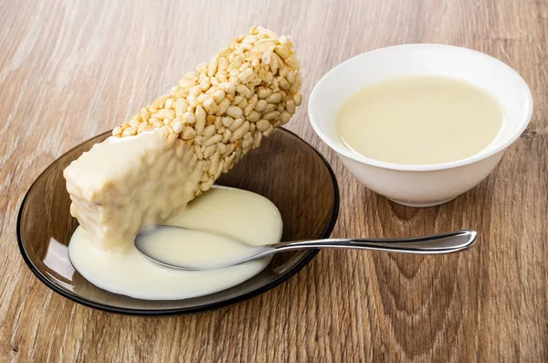 Condensed milk poured on puffed rice, spoon in saucer, bowl with