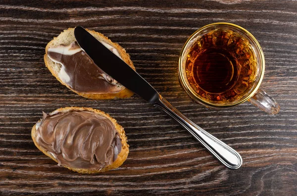 Sandwiches with chocolate-nut paste, knife and cup of tea on tab