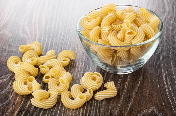 Transparent bowl with raw pasta cavatappi, pasta on wooden table