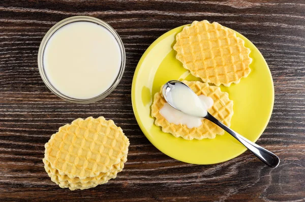 Stack of cookies, condensed milk in spoon on cookie in saucer, b