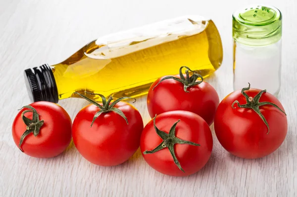 Bottle of vegetable oil, salt, red tomatoes on wooden table