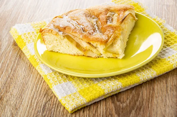 Piece of pie (charlotte) in saucer on napkin on wooden table