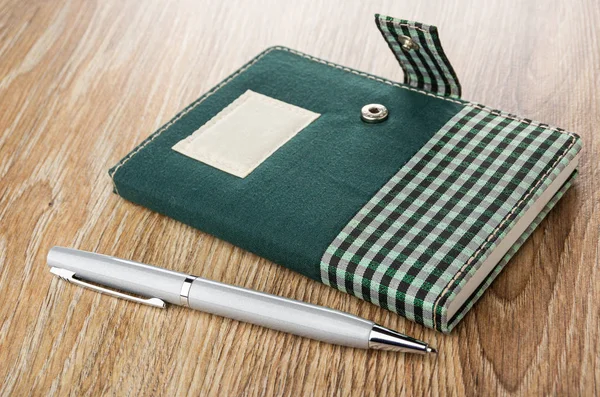 Notepad with cloth cover, ballpoint on wooden table